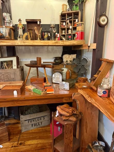 Mike's live-edge wood shelving stocked with vintage tins, an antique fan, and wooden crates